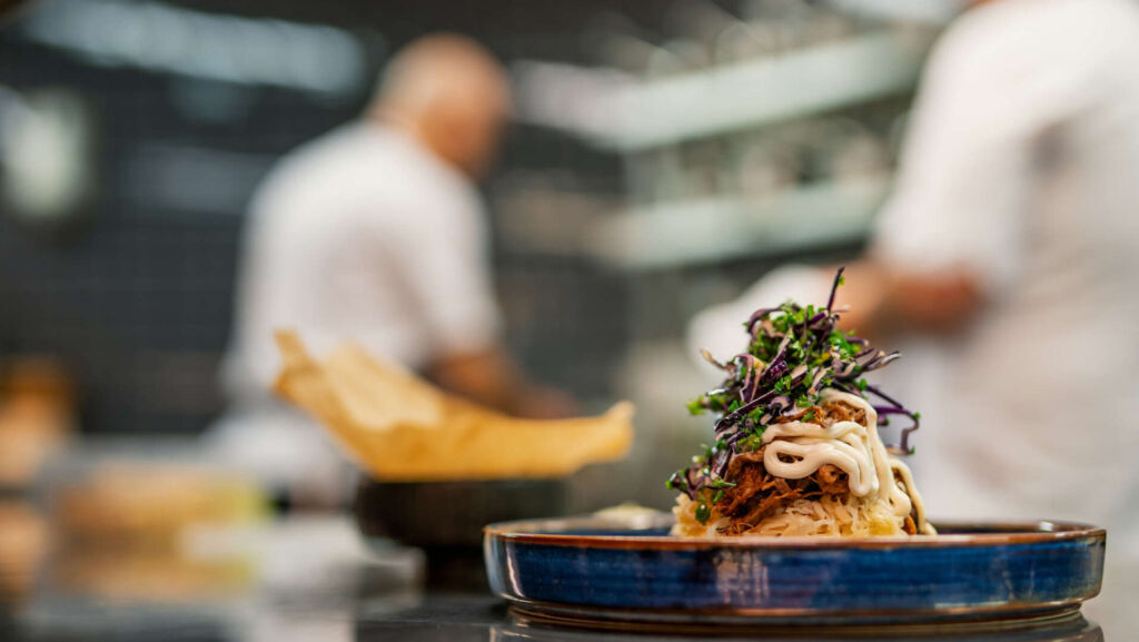 Kockar som lagar mat, i förgrunden en maträtt