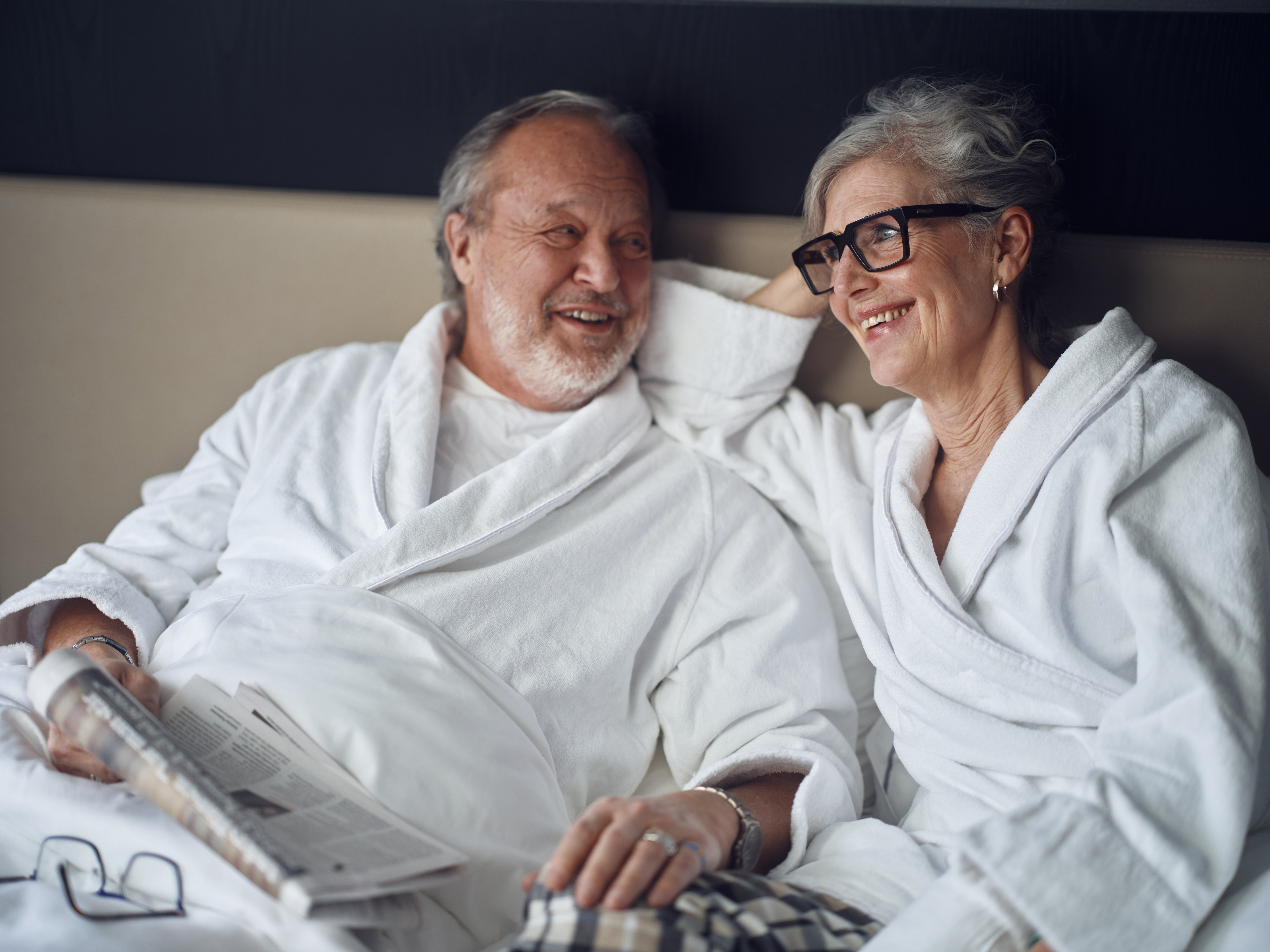 Äldre par i morgonrockar som kopplar av tillsammans på hotellrum