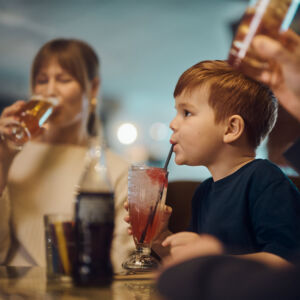 Barn och vuxna vid lunchbord på restaurangen Corner, med mat och dryck i en livfull restaurangmiljö.