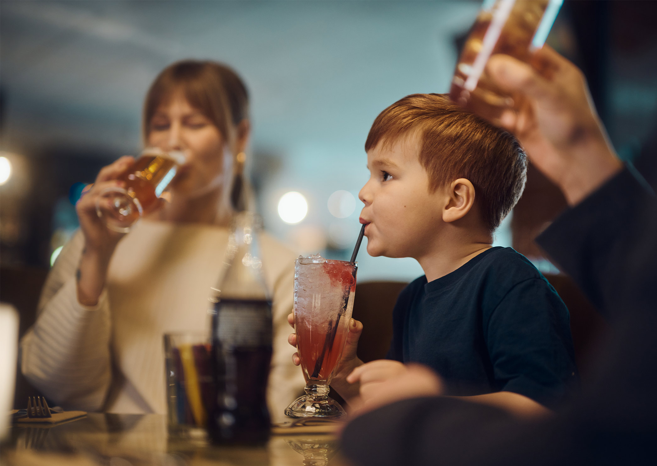 Barn och vuxna vid lunchbord på restaurangen Corner, med mat och dryck i en livfull restaurangmiljö.